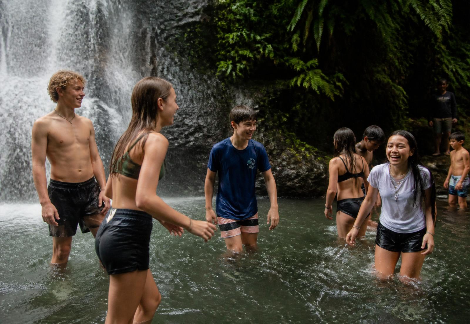 Neurodiverse children playing under a Bali waterfall during Winta's Place after-school care in Ubud.